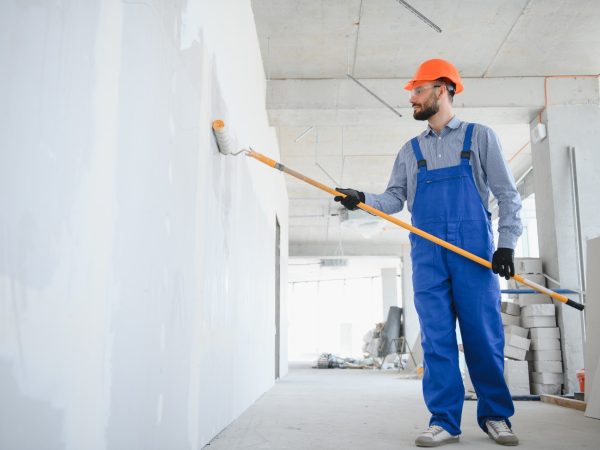Painter in uniform paints the wall